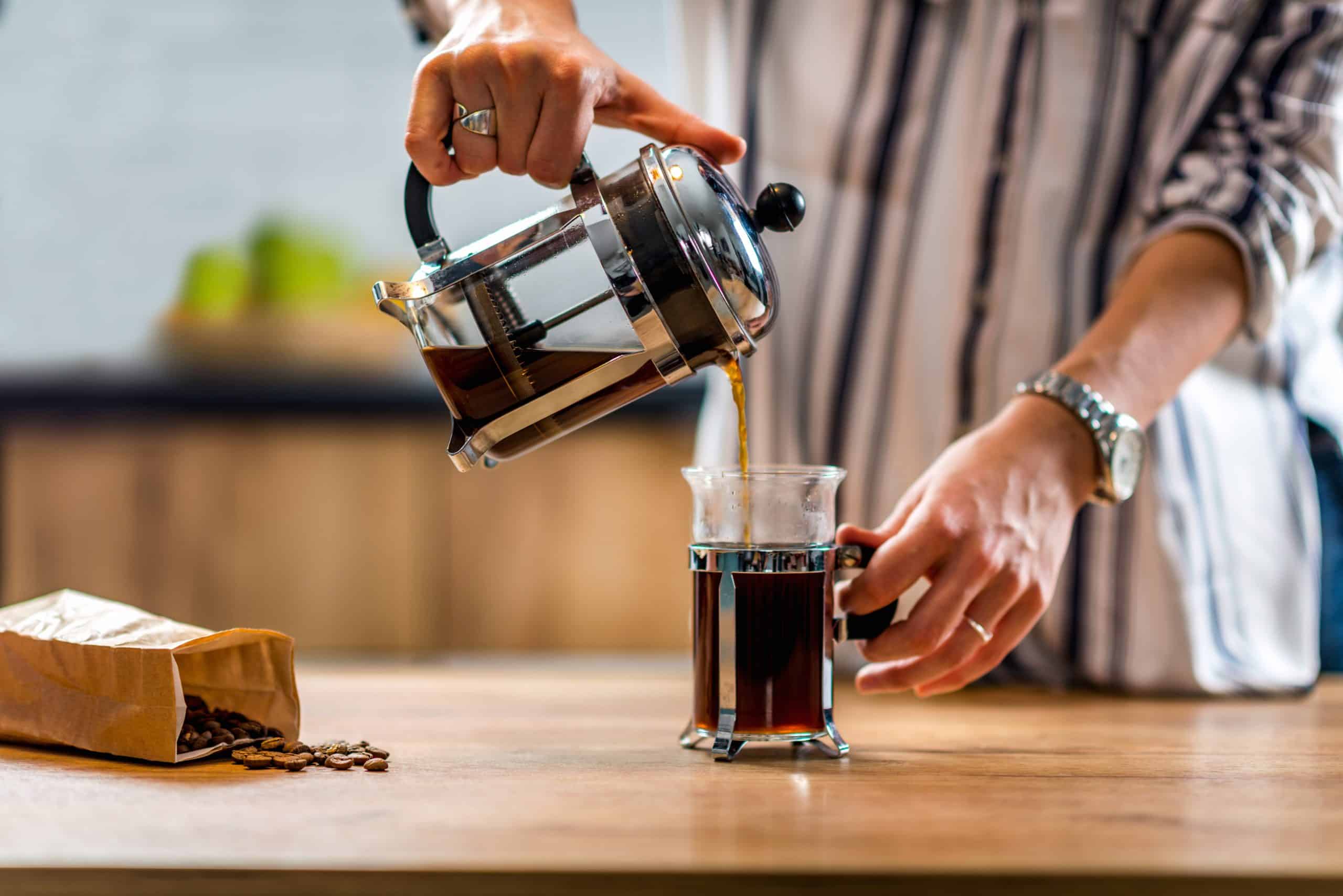 Man pouring a cup of coffee from a French press.