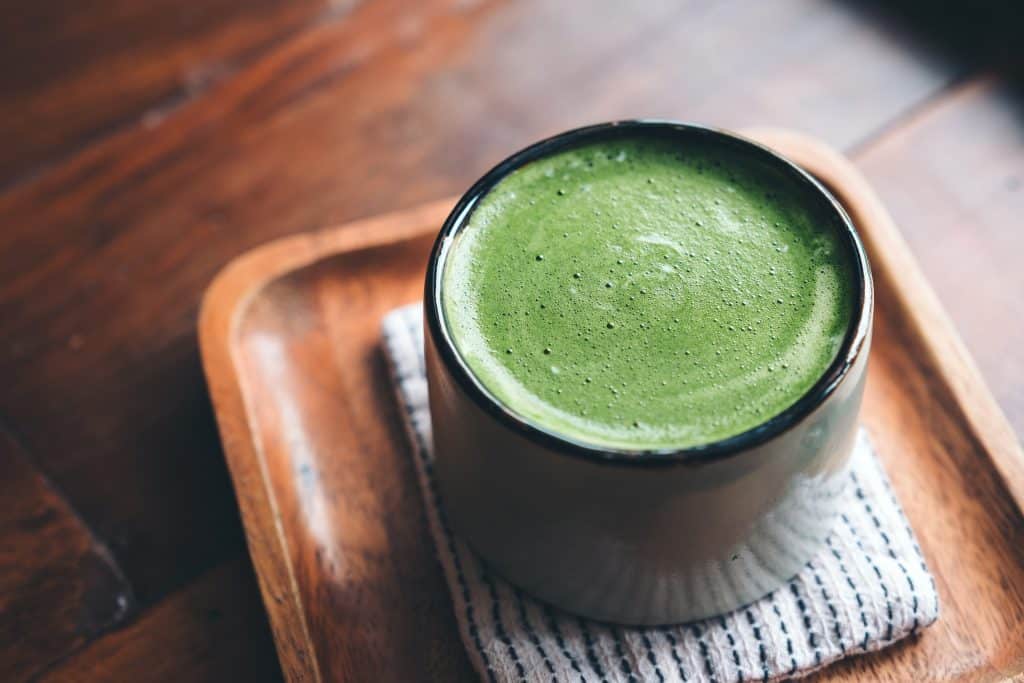 A cup of matcha on a wooden tray.