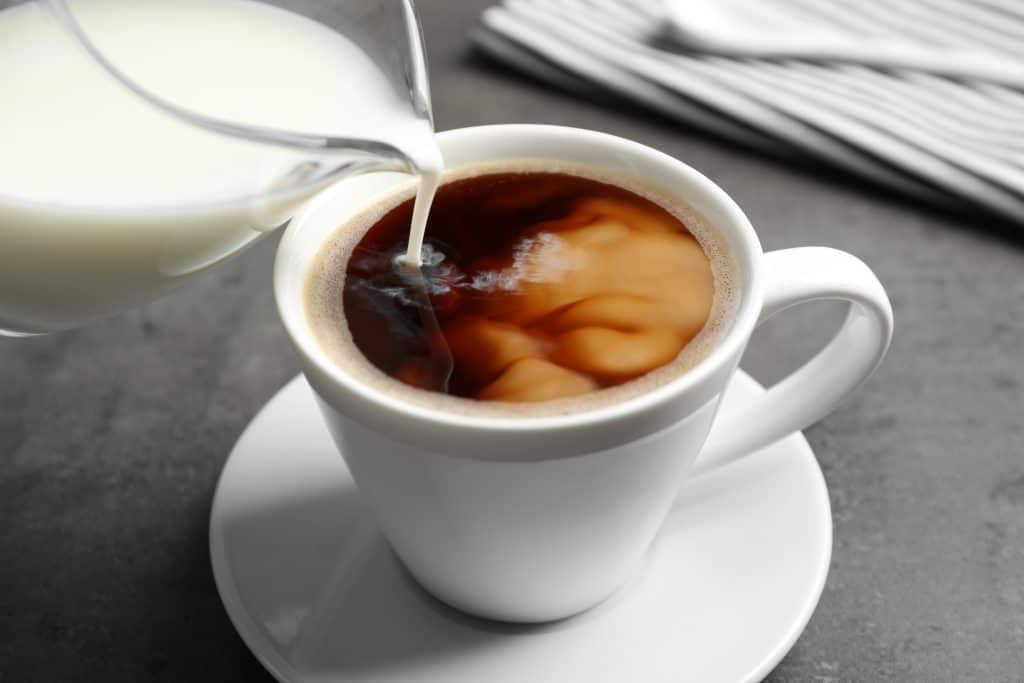 Milk being poured into a cup of coffee.