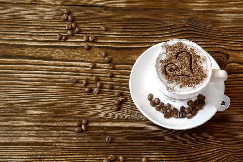 Cup of coffee with a latte art stencil sitting on top. 